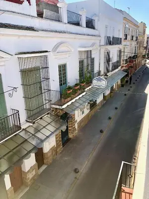 an empty street next to a white building with balconies at GATU PREMIUM La Casa del Arco con wifi, aire acc, terraza ,