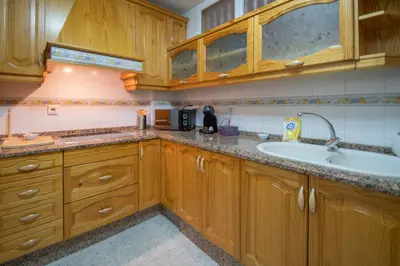 a kitchen with wooden cabinets and a sink at Apartamento Nuestra Andalucia - Cadiz Centro - parking in Cádiz