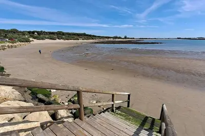 a beach with a person walking on the sand at Casa con encanto junto a la playa de La Puntilla in El Puerto de Santa María