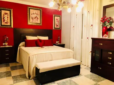 a bedroom with red walls and a bed with red pillows at Casa grande con piscina in Rota