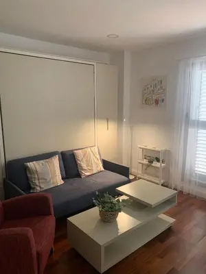 a living room with a blue couch and a table at Estudio Alameda in Cádiz