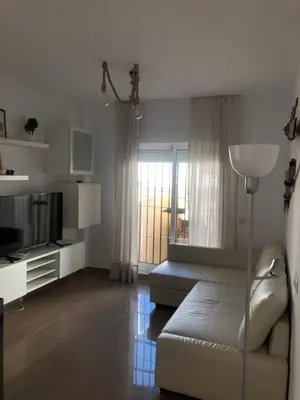 a living room with a white couch and a television at Terraza Mirador del Coto in Sanlúcar de Barrameda