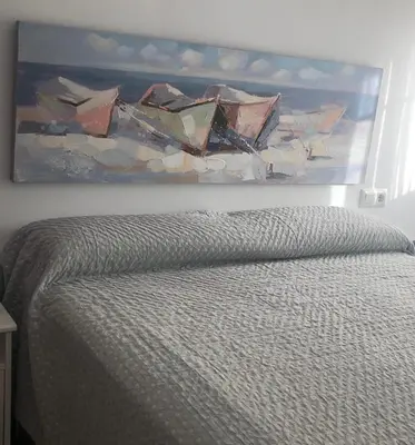 a painting on a wall above a bed at Terraza Mirador del Coto in Sanlúcar de Barrameda