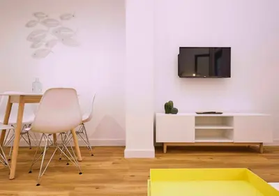a living room with a table and a tv on a wall at Precioso duplex con patio junto a la Catedral in Cádiz