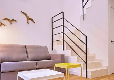 a living room with a couch and a staircase at Precioso duplex con patio junto a la Catedral in Cádiz