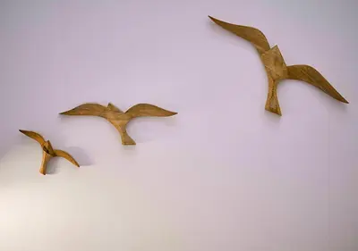 three wooden birds hanging on a white wall at Precioso duplex con patio junto a la Catedral in Cádiz