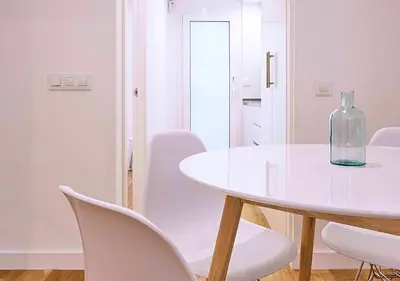 a white dining room with a glass bottle on a table at Precioso duplex con patio junto a la Catedral in Cádiz