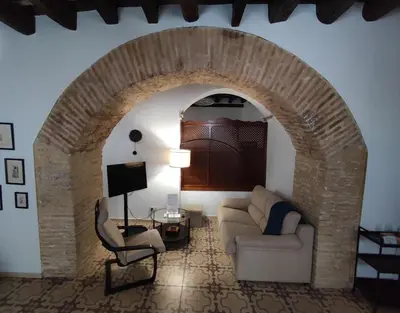 a living room with a stone archway with a couch and chair at CASA MONTAÑA in Arcos de la Frontera