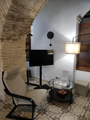 a living room with a chair a table and a television at CASA MONTAÑA in Arcos de la Frontera