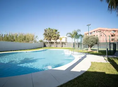 a swimming pool in a yard with palm trees and a building at SibsSanlucar Manzanilla-Piscina-Terraza-BajoGuia-Playa-Centro in Sanlúcar de Barrameda