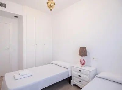 two beds in a white room with a lamp on a night stand at SibsSanlucar Manzanilla-Piscina-Terraza-BajoGuia-Playa-Centro in Sanlúcar de Barrameda