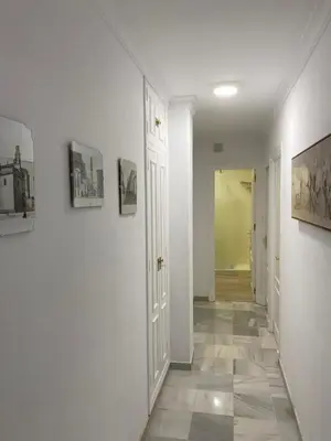 a hallway with white walls and a tile floor at Apartamento céntrico “Los Pajaritos” con garaje. in Jerez de la Frontera