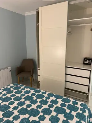 a bedroom with a bed and a closet and a chair at Apartamento céntrico “Los Pajaritos” con garaje. in Jerez de la Frontera
