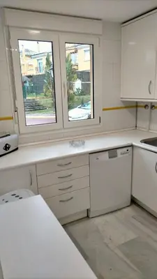 a kitchen with white cabinets and two windows at Entre hoyos y la playa Grupo AC Gestion in Novo Sancti Petri