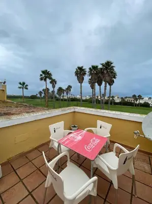 a table and chairs on a balcony with palm trees at Entre hoyos y la playa Grupo AC Gestion in Novo Sancti Petri