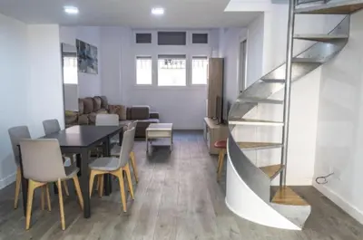 a dining room with a table and a spiral staircase at Brisa Marinera Grupo AC Gestion in Cádiz