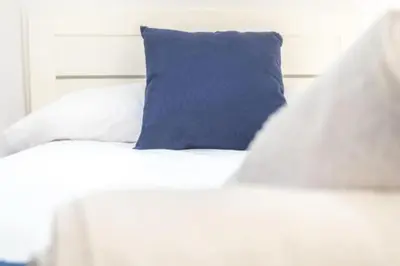 a white bed with a blue pillow on it at Brisa Marinera Grupo AC Gestion in Cádiz