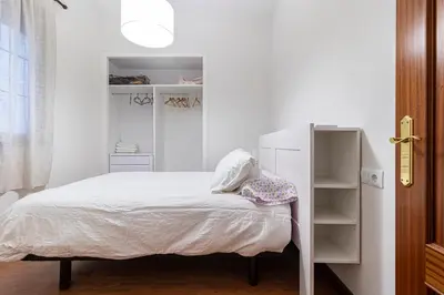 a white bedroom with a bed and a book shelf at Allo Apartments Remedios Centro 2 Habitaciones in Jerez de la Frontera