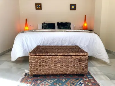 a bedroom with a large bed with a wicker table at GATU PREMIUM Atico Sotavento playa, parking, terraza, piscinas, wifi y aire acc , 