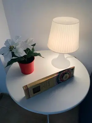 a table with a lamp and a clock and a plant at Palma 2 sueños in Jerez de la Frontera