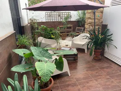 a patio with chairs and an umbrella and plants at Palma 2 sueños in Jerez de la Frontera