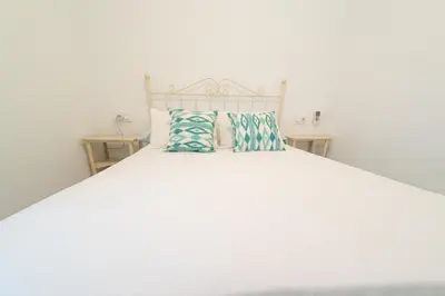 a white bed with two pillows on top of it at Apartamento Centro Calle Plata in Sanlúcar de Barrameda