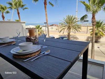 a blue table with a plate of food on a balcony with palm trees at Boutelou playa con vistas al mar in Sanlúcar de Barrameda