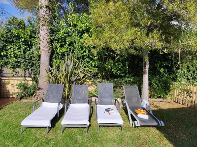 three chairs and a table in a yard with trees at Casa Juanse in Conil de la Frontera