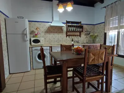 a kitchen with a table and a white refrigerator at Casa Juanse in Conil de la Frontera