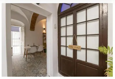 a brown door in a white wall with a stairs at Casa Cuna in Arcos de la Frontera