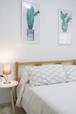a bedroom with a bed and a table with a cactus at Cielos 57 in El Puerto de Santa María
