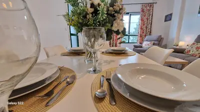 a dining room table with plates and a vase of flowers at Guadalquivir amplio y céntrico in Sanlúcar de Barrameda