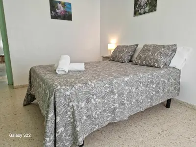 a bedroom with a bed with a gray blanket and pillows at Guadalquivir amplio y céntrico in Sanlúcar de Barrameda