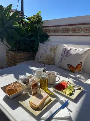 a breakfast tray with bread and vegetables on a bed at La Gitanilla Alojamiento & Encanto Jerez in Jerez de la Frontera