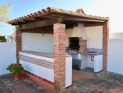 an outdoor pizza oven with a roof on a patio at Fuente del Gallo Nomada in Conil de la Frontera