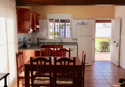 a kitchen with a table and chairs and a refrigerator at Fuente del Gallo Nomada in Conil de la Frontera