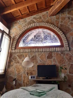 a room with a stone wall with a window and a tv at Casa Grande Zona Norte in Jerez de la Frontera