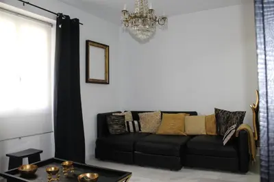 a black couch in a living room with a chandelier at Luxury apartament in Cádiz