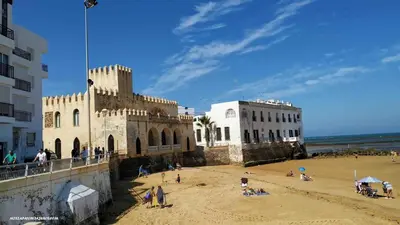 a group of people on a beach next to a building at Apartamento en la playa cruz del mar chipiona in Chipiona