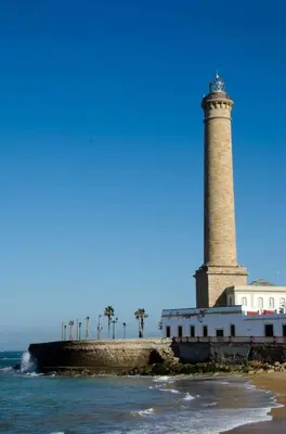 a lighthouse on the shore of the ocean at Apartamento en la playa cruz del mar chipiona in Chipiona
