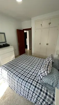 a bedroom with a bed with a blue and white checkered blanket at Apartamento en la playa cruz del mar chipiona in Chipiona
