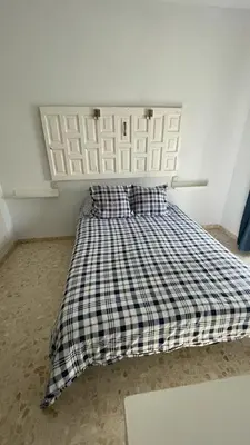 a bed with a checkered blanket and two pillows at Apartamento en la playa cruz del mar chipiona in Chipiona