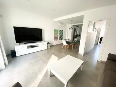 a living room with a large flat screen tv at Casa moderna, piscina, playa, TV75, Netflix, PS4 in Conil de la Frontera