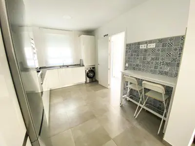 a kitchen with a counter and a table with chairs at Casa moderna, piscina, playa, TV75, Netflix, PS4 in Conil de la Frontera