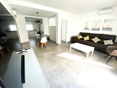 a living room with a couch and a table at Casa moderna, piscina, playa, TV75, Netflix, PS4 in Conil de la Frontera