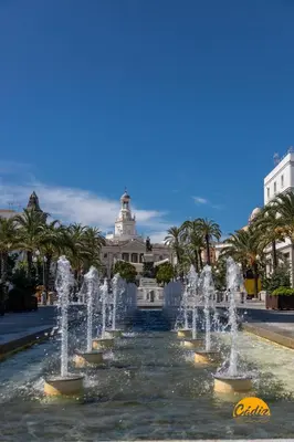 a fountain in front of a building with palm trees at La Casa del Alfarero by Cadiz Time in Cádiz
