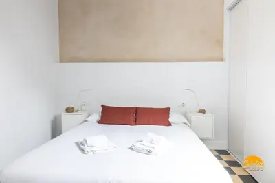 a bedroom with a white bed with two towels on it at La Casa del Alfarero by Cadiz Time in Cádiz