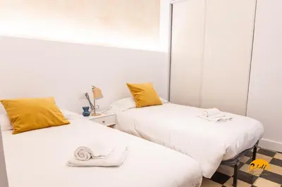 two beds in a room with white walls and yellow pillows at La Casa del Alfarero by Cadiz Time in Cádiz