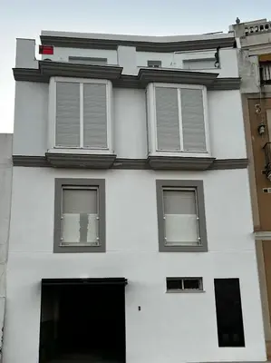 a white building with three windows on it at Ático Good Vibes in Rota