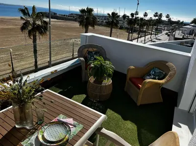 a balcony with two chairs and a table and a view of the beach at Ático Good Vibes in Rota